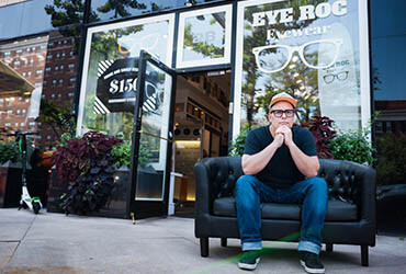 Man sitting outside Eye Roc Eyecare & Eyewear eyeglasses shop.