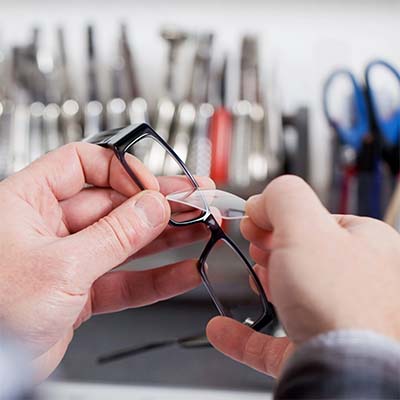 Close up of man holding eyeglasses frames for repair.