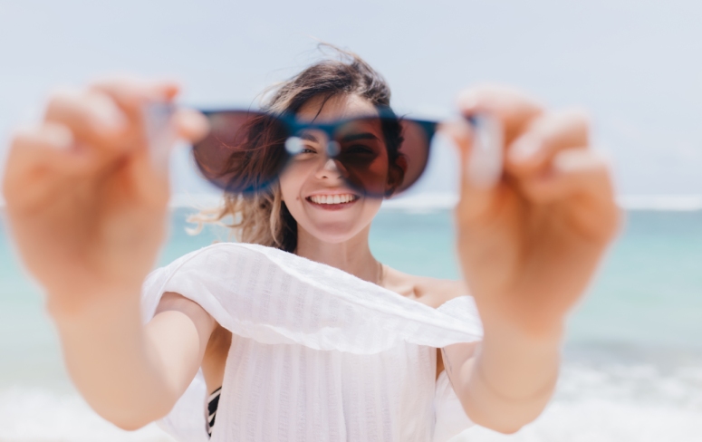 joyful-tanned-woman-playfully-posing-with-sunglasses-sea-outdoor-photo-pretty-young-woman-fooling-around-beach (1)